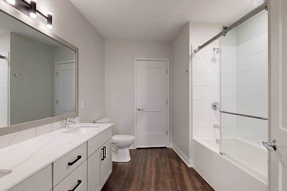 A white bathroom with a toilet, sink, and a walk-in shower.