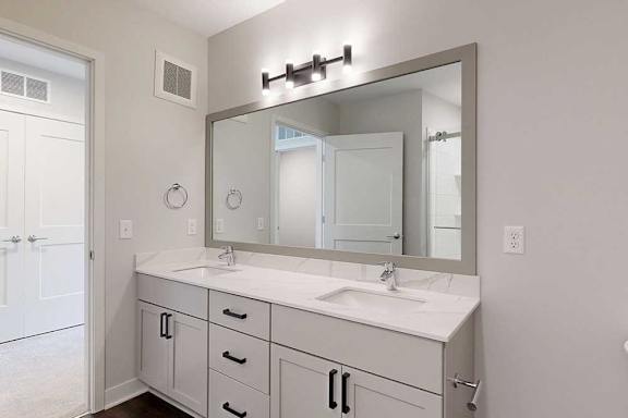 A bathroom with a white vanity and a large mirror.