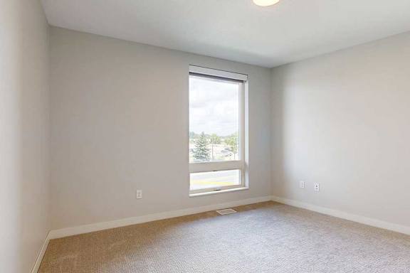 A room with a window and a carpeted floor.