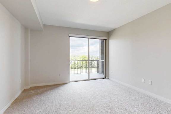 A bedroom with a sliding glass door leading to a balcony.