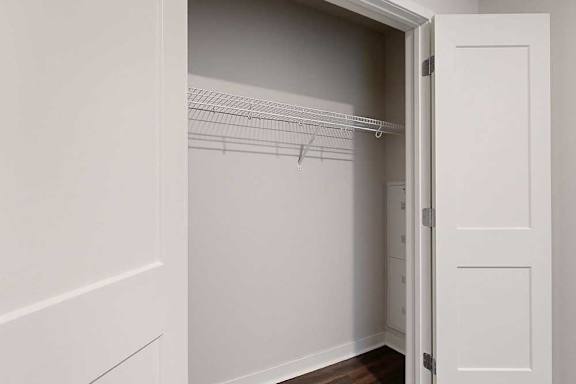 A white closet with a door open and shelves.