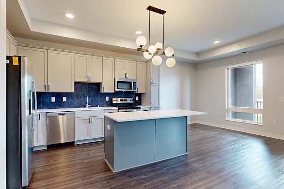 A modern kitchen with a large island and stainless steel appliances.
