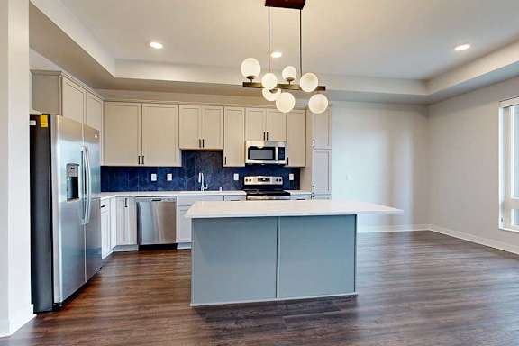 A modern kitchen with a refrigerator, microwave, and stove top oven.