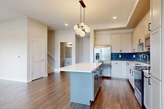 A modern kitchen with a center island and stainless steel appliances.