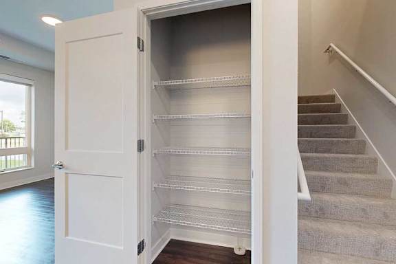 Empty shelves in a closet next to a staircase.