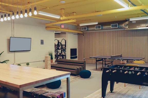 The bike lounge room with a foosball table, board games, a TV, Jenga, and a ping-pong table.