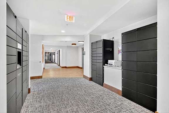 A hallway with a carpeted floor and a white wall with a black door on the right.