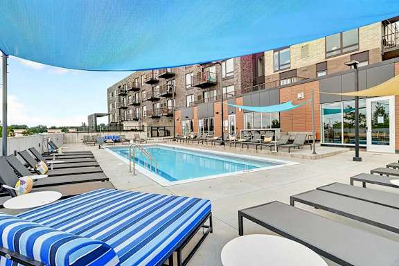 A pool area with sun loungers and a striped awning.