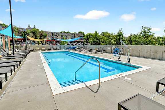 A large outdoor swimming pool with a blue sky and clouds in the background.