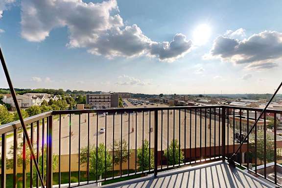 A balcony overlooks a cityscape with buildings and greenery.