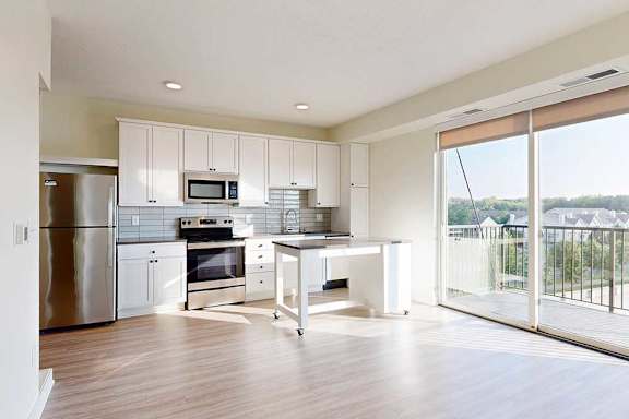 Modern kitchen with white cabinets, stainless steel appliances, including a fridge, oven, and microwave.