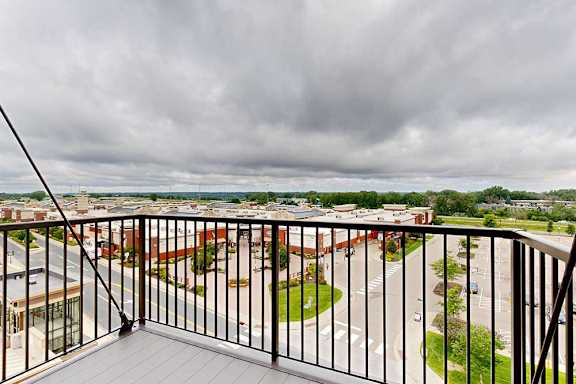 A balcony overlooks a parking lot and buildings.