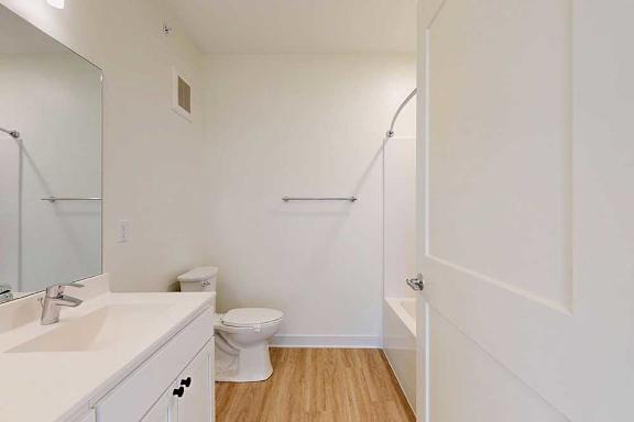 A white bathroom with a toilet, sink, and a shower.
