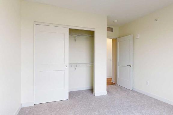 A white closet door is open in a bedroom with carpeted floor.