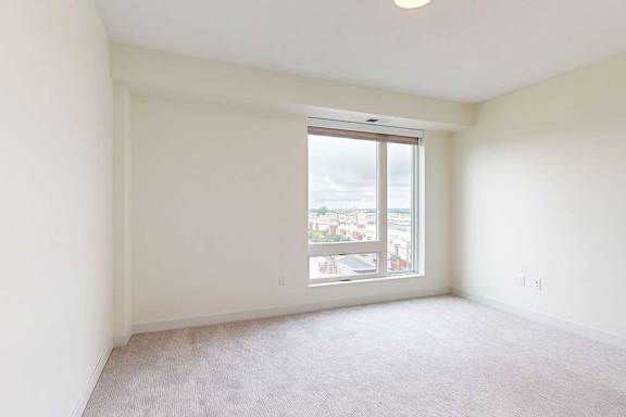 A large empty bedroom with a window overlooking a cityscape.