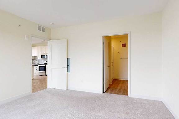 A white room with a carpeted floor and two open doors.