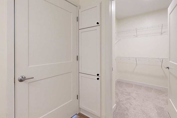 White walk-in closet with beige carpet and wire shelving against cream walls.