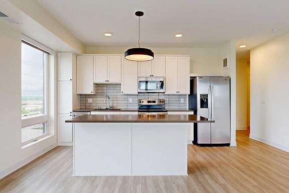 A modern kitchen with white cabinets and a wooden floor.