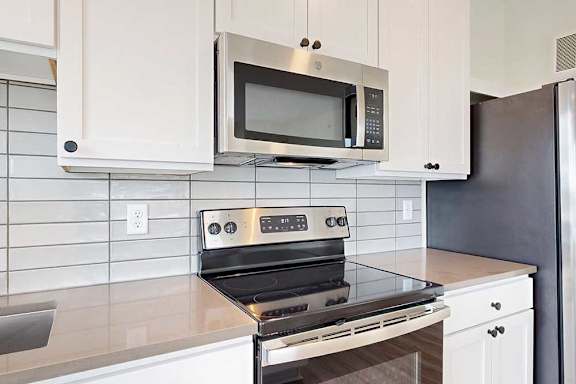 A modern kitchen with a stainless steel oven and microwave above it.