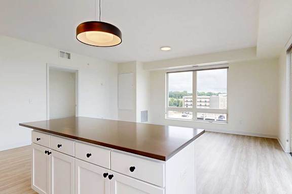 A kitchen with white cabinets and an island with brown countertop.