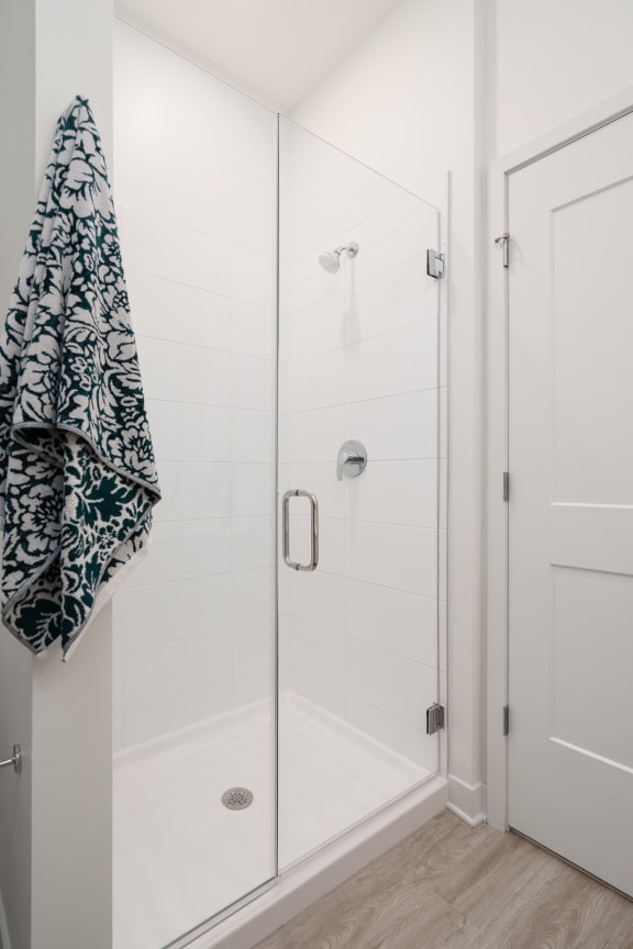 Walk in shower with glass door and towel hanging on rack to the right