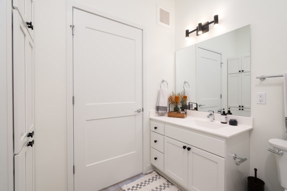 White bathroom vanity with large mirror and towel hanging on rack
