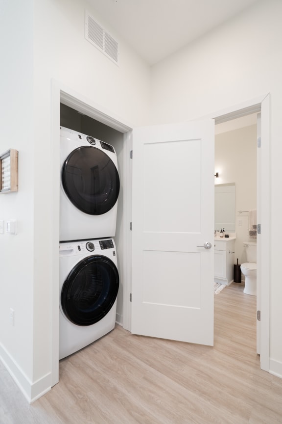 Stacked washer and dryer in laundry closet with door open