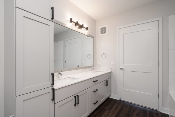 large white double vanity with large mirror and tall storage cabinet on the right
