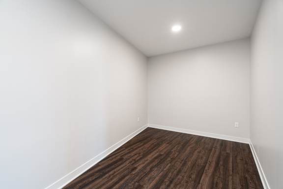 perfect size den with white walls and dark brown hard wood flooring