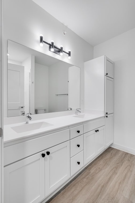 Bathroom with white double vanity and linen cabinet for storage and large mirror at The Rowan in Eagan Minnesota