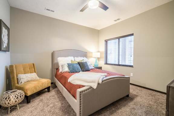A bedroom with a bed, chair, and window.