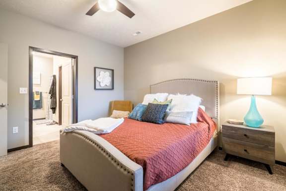 A bedroom with a large bed and a ceiling fan.