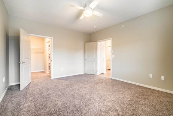 A spacious room with a ceiling fan and carpeted floor.