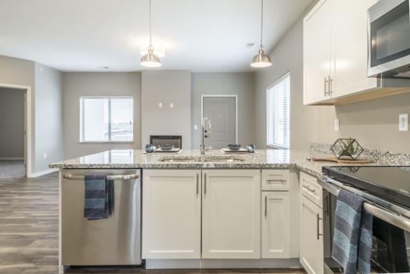Contemporary kitchen with white cabinetry, light granite countertops and stainless steel appliances at The Villas at Falling Waters