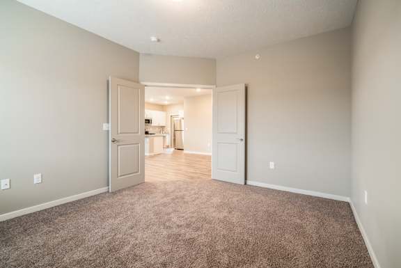 A room with a carpeted floor and two doors.