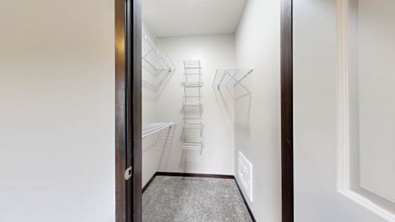 A walk-in closet with a carpeted floor and white walls.