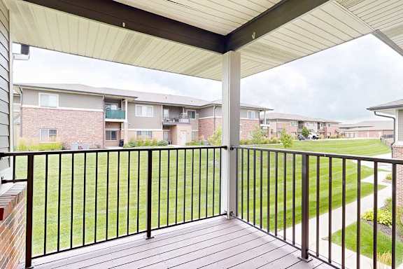 A corner balcony with a metal railing and a view of the neighborhood.