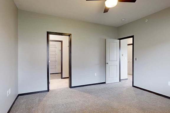 A carpeted bedroom with an attached bathroom connected to a walk-in closet.