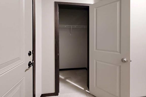 A coat closet in the main entryway with a built-in wire shelf.