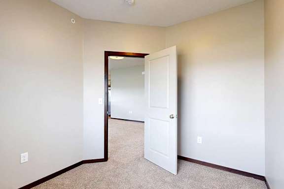 A carpeted den space with a door open to the living room.