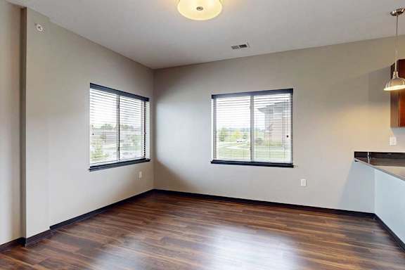 A dining area with large windows and hardwood-style flooring next to the kitchen.