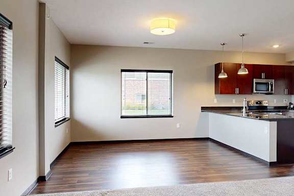 A dining area with large windows and hardwood-style flooring next to the kitchen.