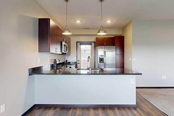 A kitchen with dark wooden cabinets, granite countertops, stainless steel appliances, and a peninsula countertop.
