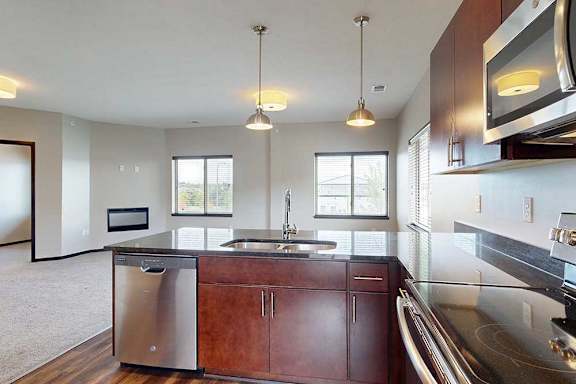 A kitchen peninsula with a double basin sink in front of a dining room and living room.