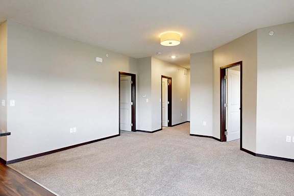 A carpeted living room connected to a den space and bedroom.