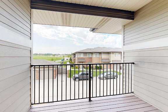 A balcony with a black metal railing and a view of the neighborhood.