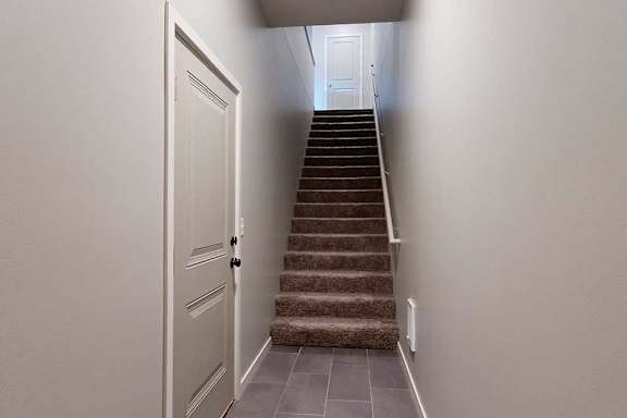 An entryway with a closed door to the attached garage, and a stairway leading up to the living area.