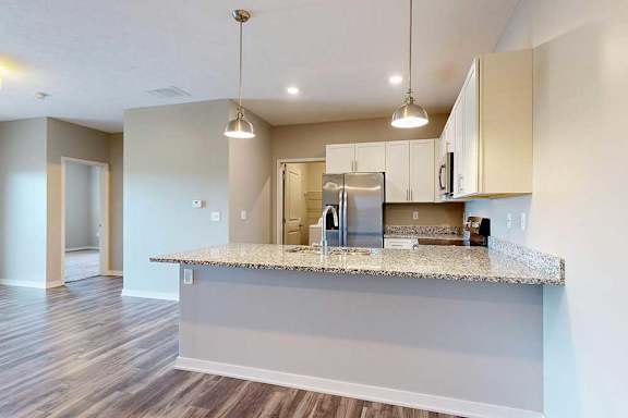 A kitchen with white wooden cabinets, granite countertops, stainless steel appliances, and a peninsula countertop.