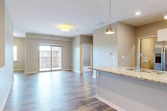 A living room with hardwood-style flooring and a sliding glass door to a balcony.