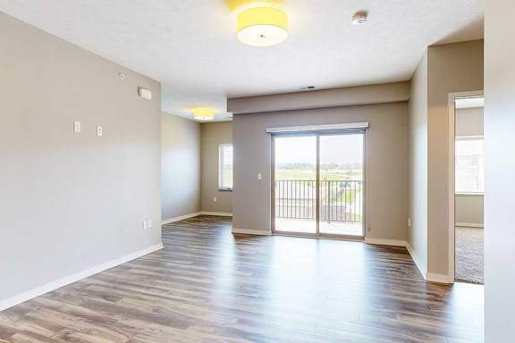 A living room with hardwood-style flooring, a sliding glass door to a balcony, and a nook in the corner.